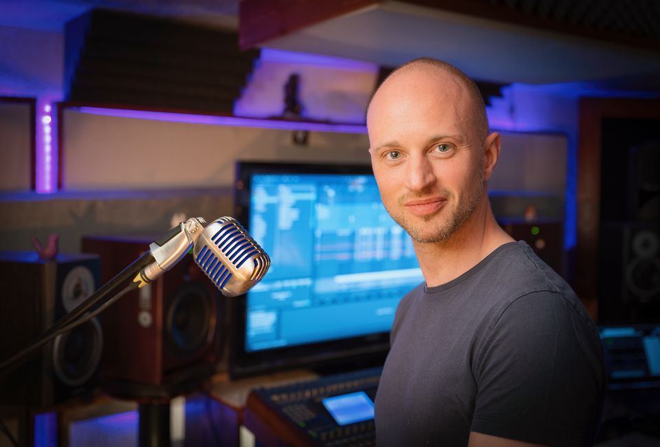 OXSA souriant dans son studio de Meyrin, devant un micro et ses écrans